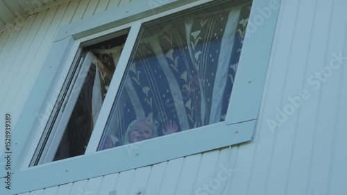 little girl stuck her head out the window, through the open window in the attic the child looks outside