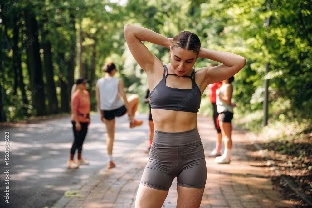 Abs, strong fitness woman is standing. Group of runners are together outdoors Abs, strong fitness woman is standing. Group of runners are together outdoors