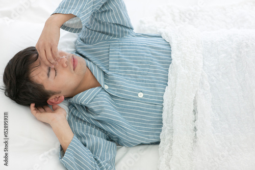 ベッドで寝るパジャマ姿の男性