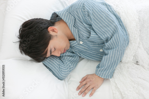 ベッドで寝るパジャマ姿の男性
