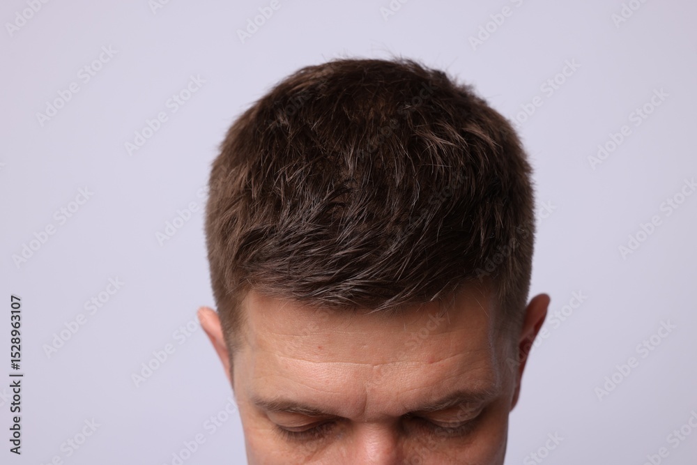 Obraz premium Man with brown hair on light background, closeup