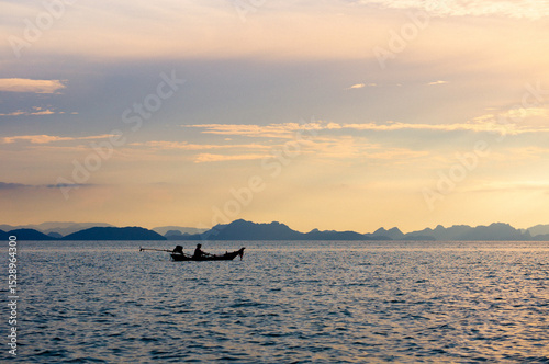 Silhouetted boat at sunset on a calm sea photo