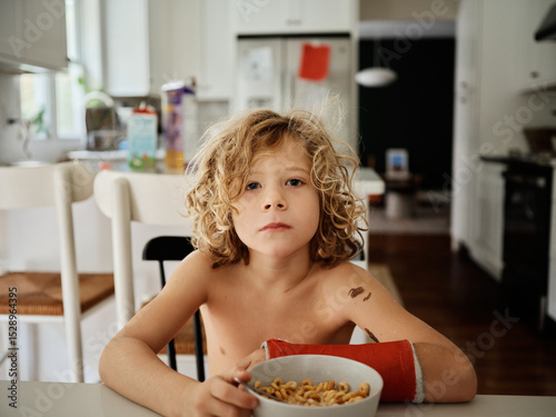 young boy eats breakfast with a broken arm