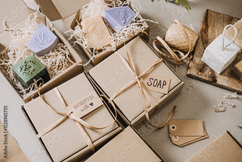 Kraft gift boxes labeled soap and handmade with love filled with artisanal bars and shredded filler. Handmade gifts, personalized packaging, conscious consumerism, slow gifting