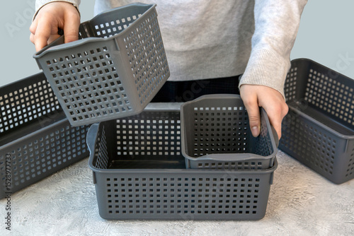 The girl uses plastic gray baskets to store things. Organization of home space, house order.
