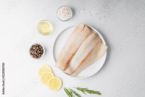 Raw pollock fillet with lemon and rosemary on white background