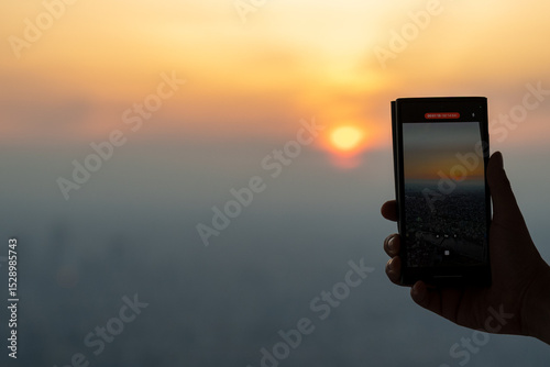 Close-up of persons hand photographing sunset through smart phone