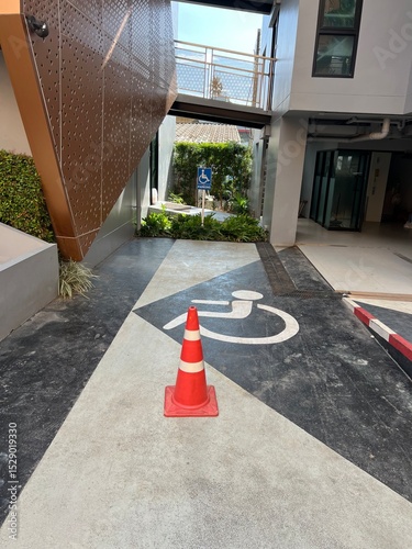 Editorial: Krabi, Thailand. June 2025. A designated accessible parking space, marked with a clear wheelchair symbol on the ground and a traffic cone. Signage in the background indicates a 