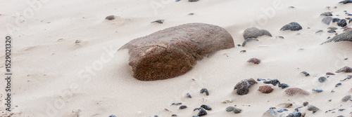 Panoramic image. Stones on the bright sandy beach