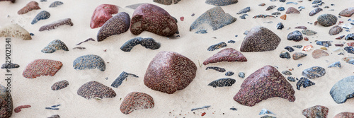 Panoramic image. Stones on the bright sandy beach