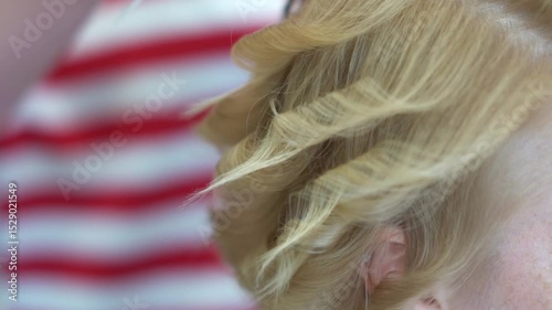 Professional hairdresser, stylist doing hairstyle on short hair - using hair straightener and comb