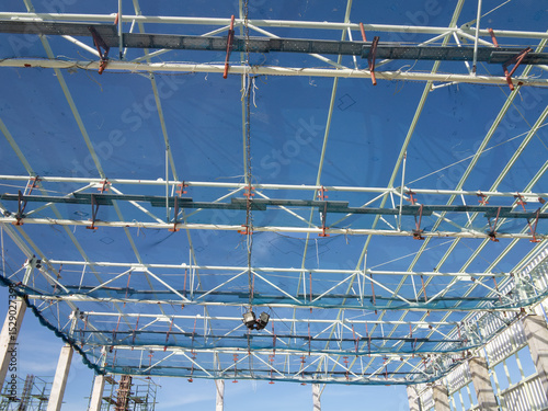 Roof under construction in construction site . To election or assembly frame truss, steel structure for cover factory warehouse building. Include scaffolding and safety net to prevent worker falling.