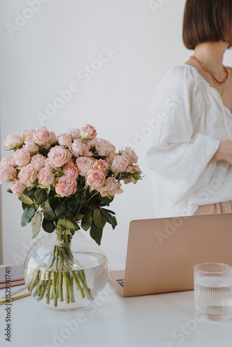 Chic office setup with pink roses and laptop. Home office workspace with floral elegance