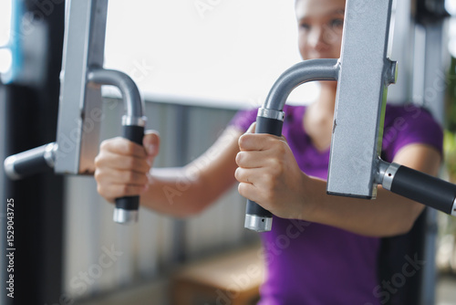 Woman exercising pectoral muscles using gym equipment