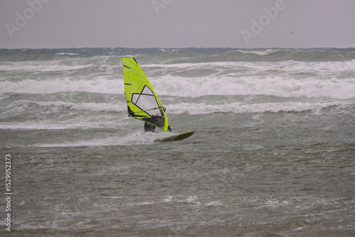 Water Sport Activity - Windsurfer Riding a Wave in Rough Sea on a Windy Day