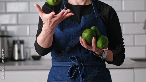 Woman In Apron Having Fun With Fresh Green Avocado In The Kitchen