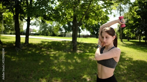 Fit Girl Doing Sport Exercises In The Park And Lifting Dumbbells As Part Of Morning Routine
