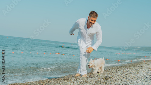 Wallpaper Mural Happy man in white clothes running along the seashore with his dog on a sunny summer day. Joyful moment of freedom, fun and connection with nature at the beach. Torontodigital.ca