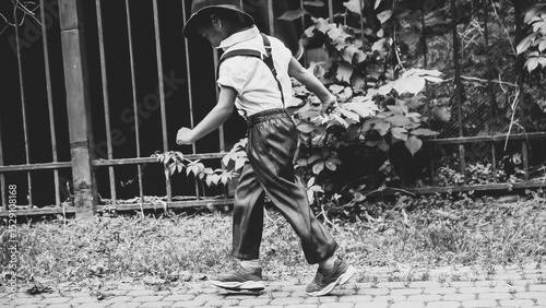 A boy dressed in the style of the 20s jumps down the street side view
