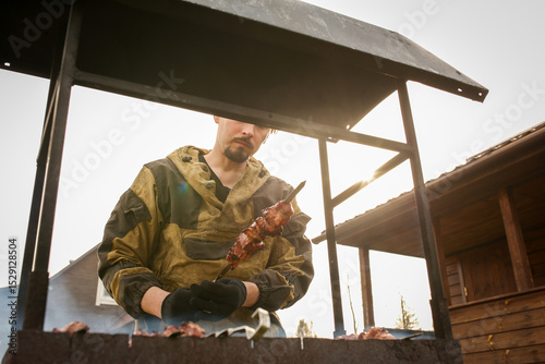 A guy roasts meat on the grill. Summer cottage season. Summer cottage. Family pastime. A celebration in the backyard.