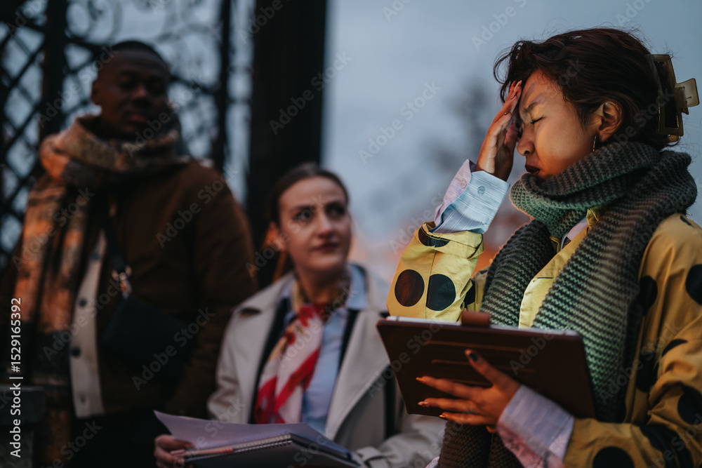 Fototapeta premium Three people of diverse backgrounds discussing and collaborating outdoors in cold weather.