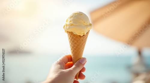 summer holliday beach. A person holding a cone of yellow ice cream against a sunny beach background, evoking a sense of summer and relaxation.