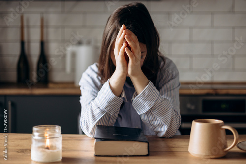 Close-up of a woman praying in her kitchen at home in the soft morning light.