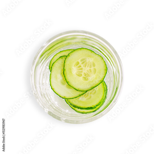 Top view of drinking glass with fresh healthy detox water drink infused with juicy refreshing cucumber vegetable circle slices isolated on white background used as cold antioxidant summer beverage