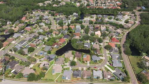 Drone shot of a peaceful suburban neighborhood featuring lush greenery, winding roads, and private backyard pools. photo