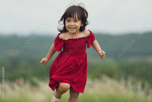 happy toddle girl in red dress running on grass field
