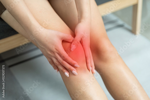 Wallpaper Mural Knee Pain Relief. Woman holding her knee in discomfort while seated. Torontodigital.ca