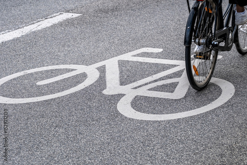 Bike symbol on asphalt with cyclist riding, Copenhagen, Denmark, eco-friendly transport infrastructure and motion concept with clean graphic space