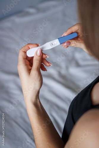 vertical photo woman holding pregnancy test. back view. positive test. pregnancy concept