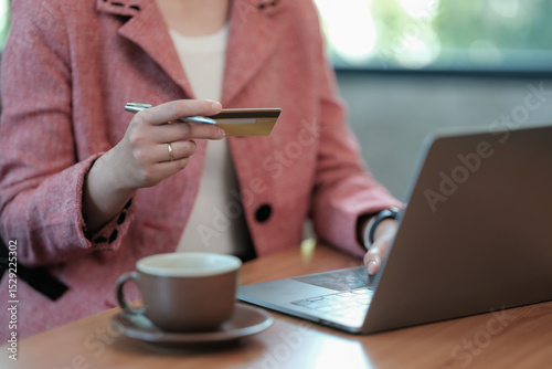 E-commerce and online banking. Close-up of a young female internet store customer, an e-bank client, making a payment from a home computer, holding a prepaid credit card in her hand.