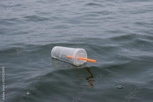 Plastic cup with straw polluting ocean water