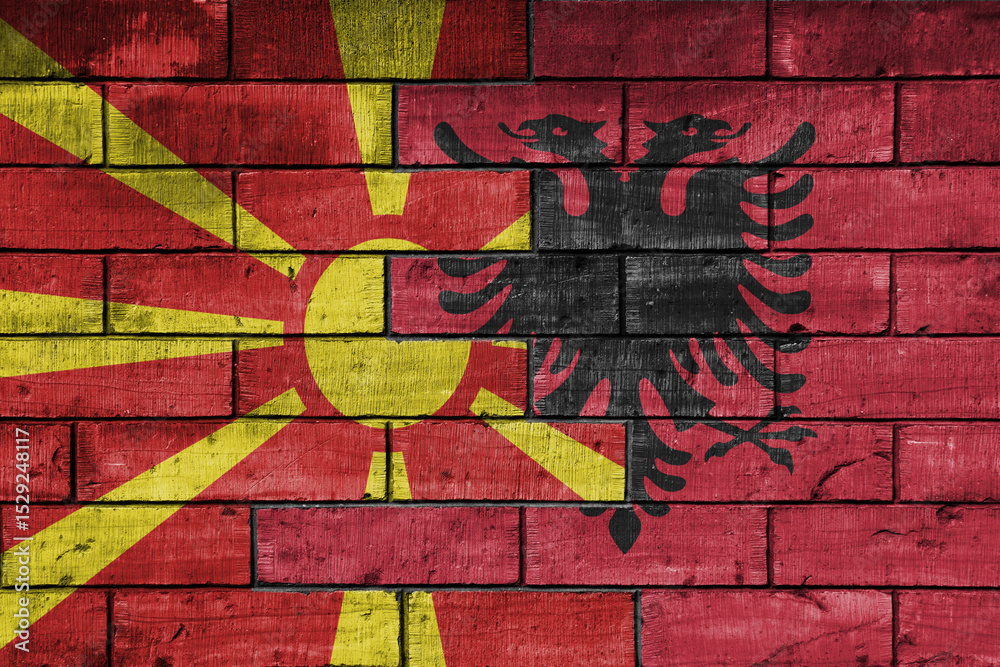 Fototapeta premium colourful painted big national flag of albania and flag of macedonia on a massive old brick wall background. concept