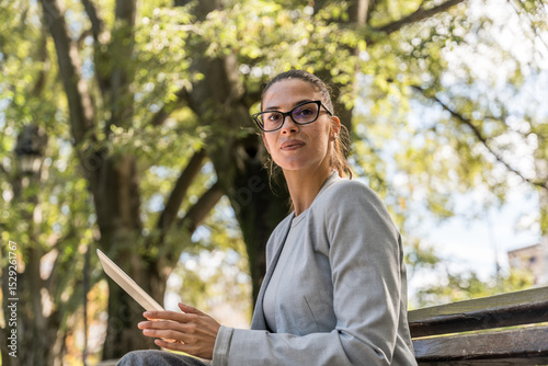 Young businesswoman sitting at park working on digital tablet, professional occupation worker, out of office building crowd concentrated and focused on business. Finance and economy expert teleworking