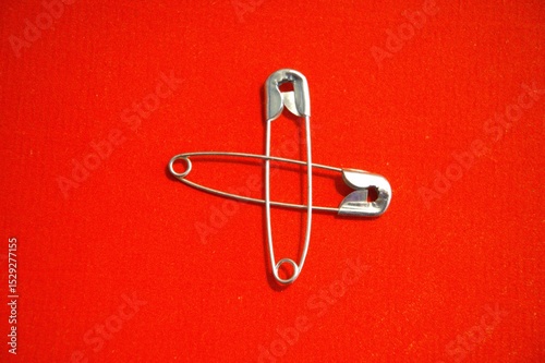 Metal safety pin with red background.