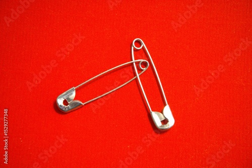Metal safety pin with red background.