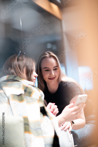 Wallpaper Mural Two young women looking at smartphone in coffee shop Torontodigital.ca
