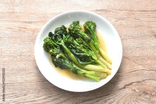 fried Kailaan Chinese kale dressing oyster sauce with chop garlic and salty fish on plate