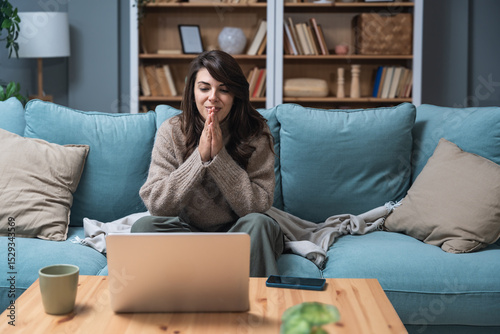 Young woman attending online therapy session from her living room, expressing emotion while talking to a professional therapist, mental health and personal growth support via digital communication.