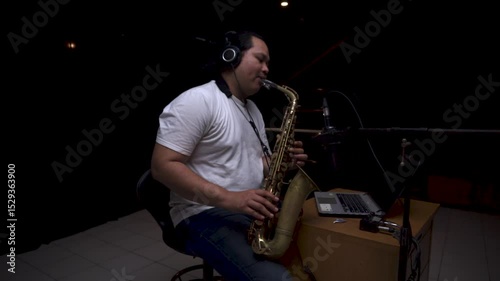 Musician Playing Saxophone in Recording Studio on dark black isolated background photo