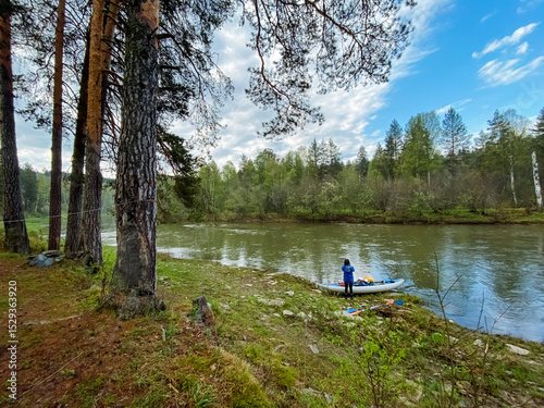 Wallpaper Mural A person is sitting in a kayak on the sandy shore of a beautiful river, surrounded by lush trees and the stunning natural landscapes that define the wilderness and forested areas Torontodigital.ca