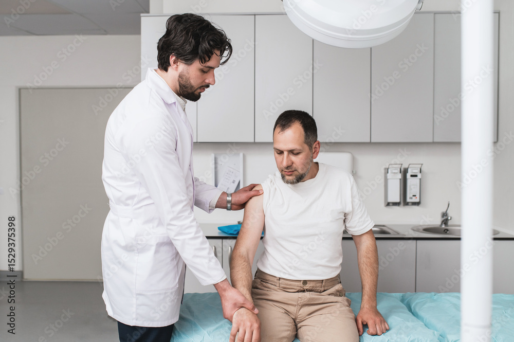 Obraz premium Doctor examining male patient with shoulder pain during physical assessment in clinic, concept of musculoskeletal disorder, orthopedic diagnosis, injury treatment, physical therapy and rehabilitation 