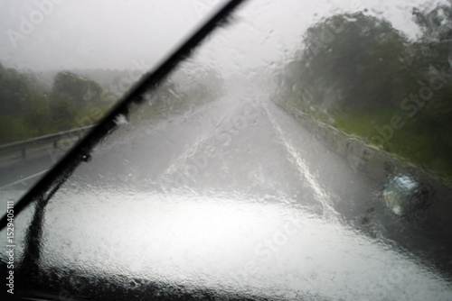 Heavy rain and American truck driving on highway. View from inside the car, car wipers cleaning the windshield