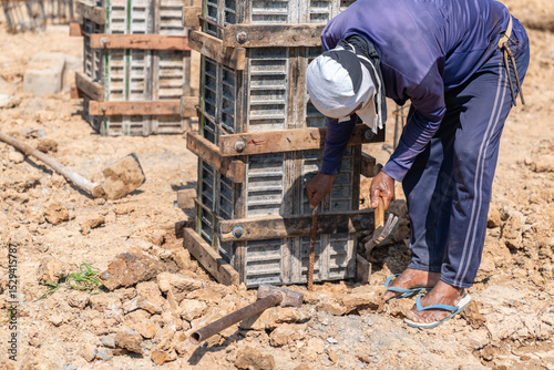 The workers drove steel rods to support the formwork for pouring the concrete column cap.
