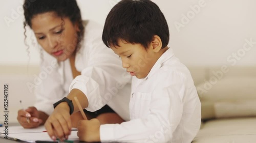 Mother helping son drawing on sofa at home