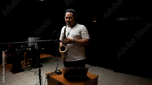 Musician Playing Saxophone in Recording Studio on dark black isolated background photo