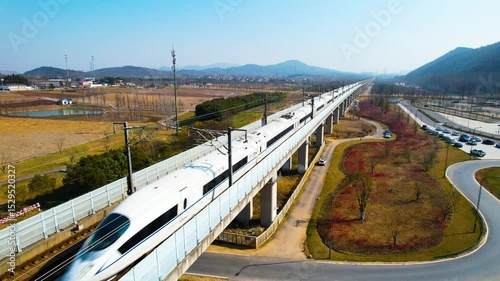 Aerial travels on Harmony high speed train tracks during daytime in China, passing over bridges and landscapes for scenic passenger transport